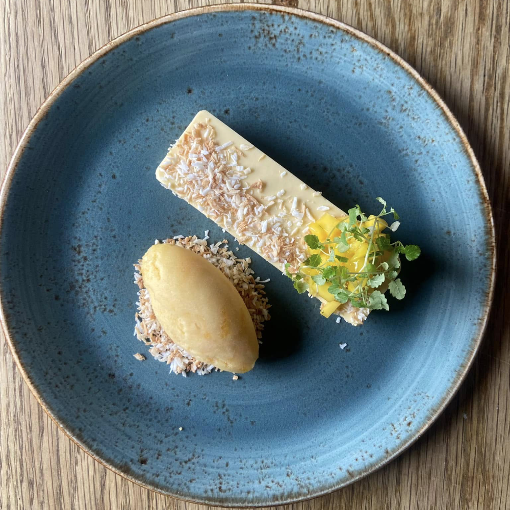 A plate of passion fruit mouse with mango sorbet and coconut crumb.