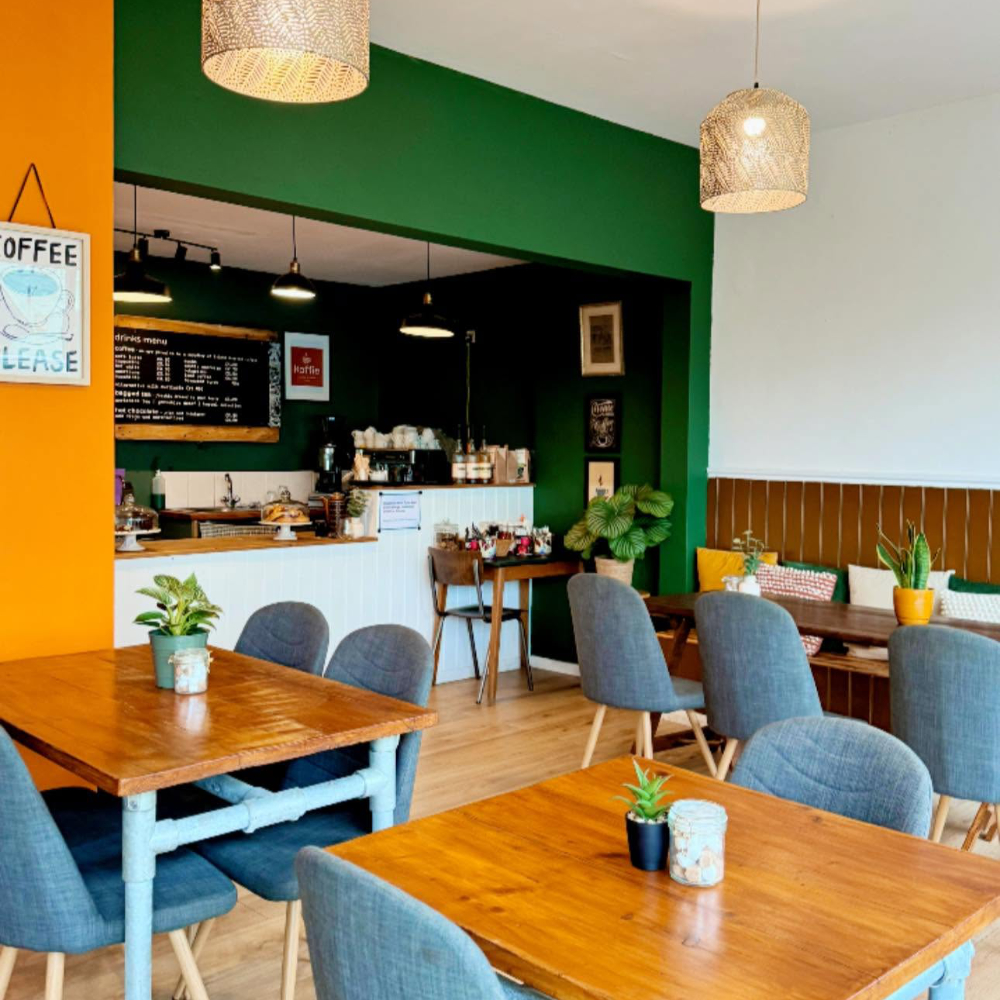 The interior of a cafe decorated in dark green and orange.
