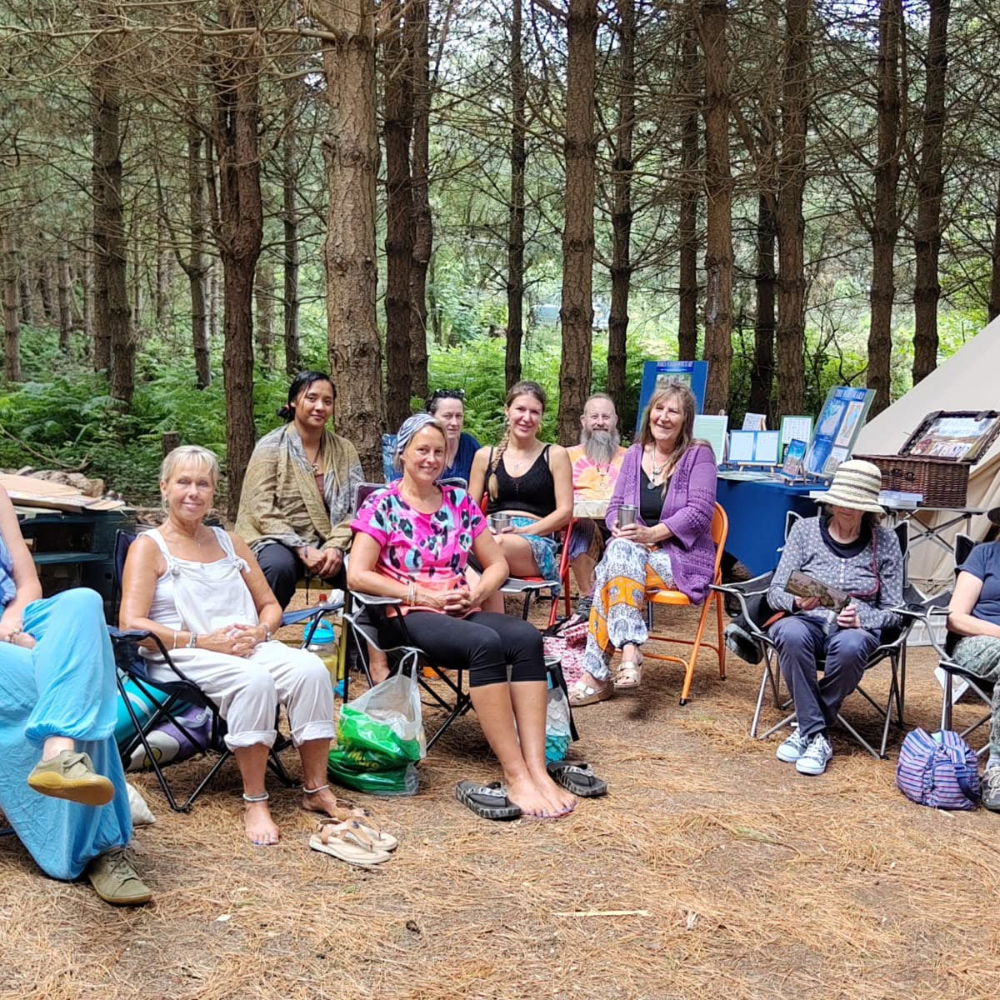 People sitting on chairs in a forest.