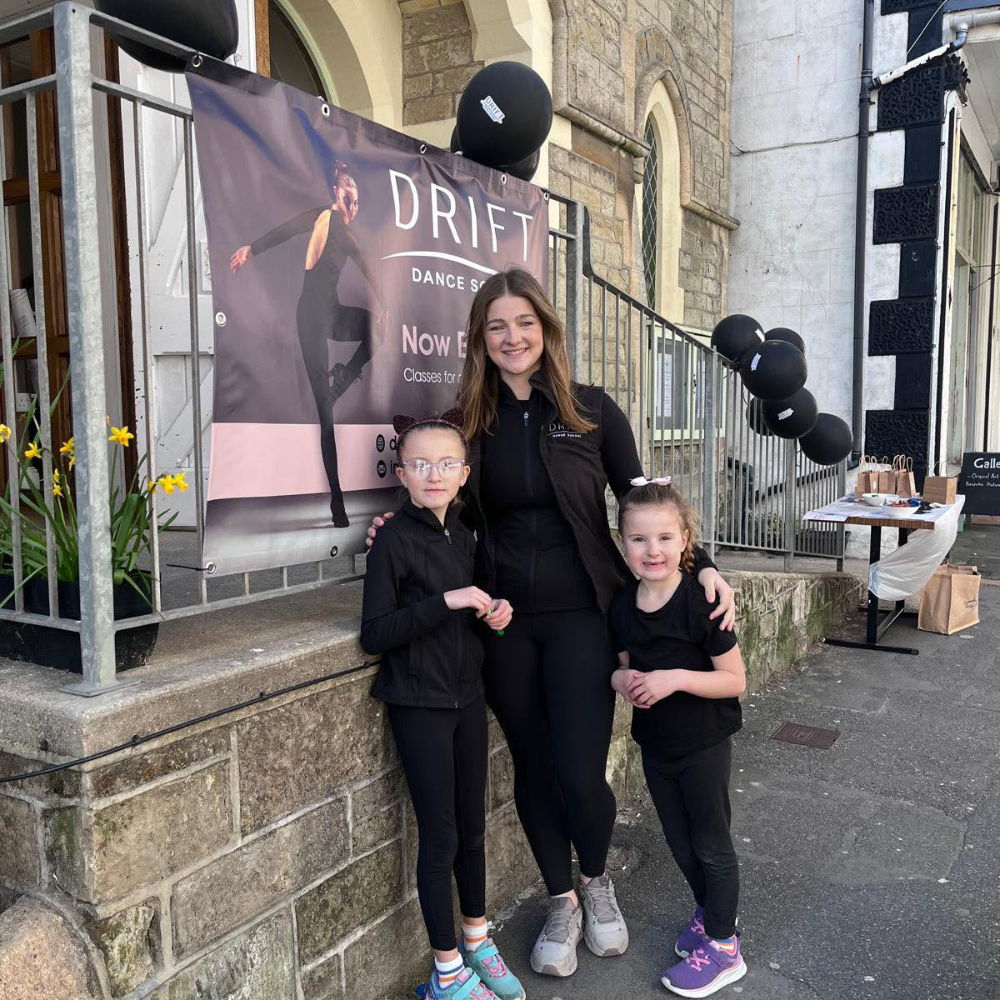 A dancer and two children standing outside a dance venue.