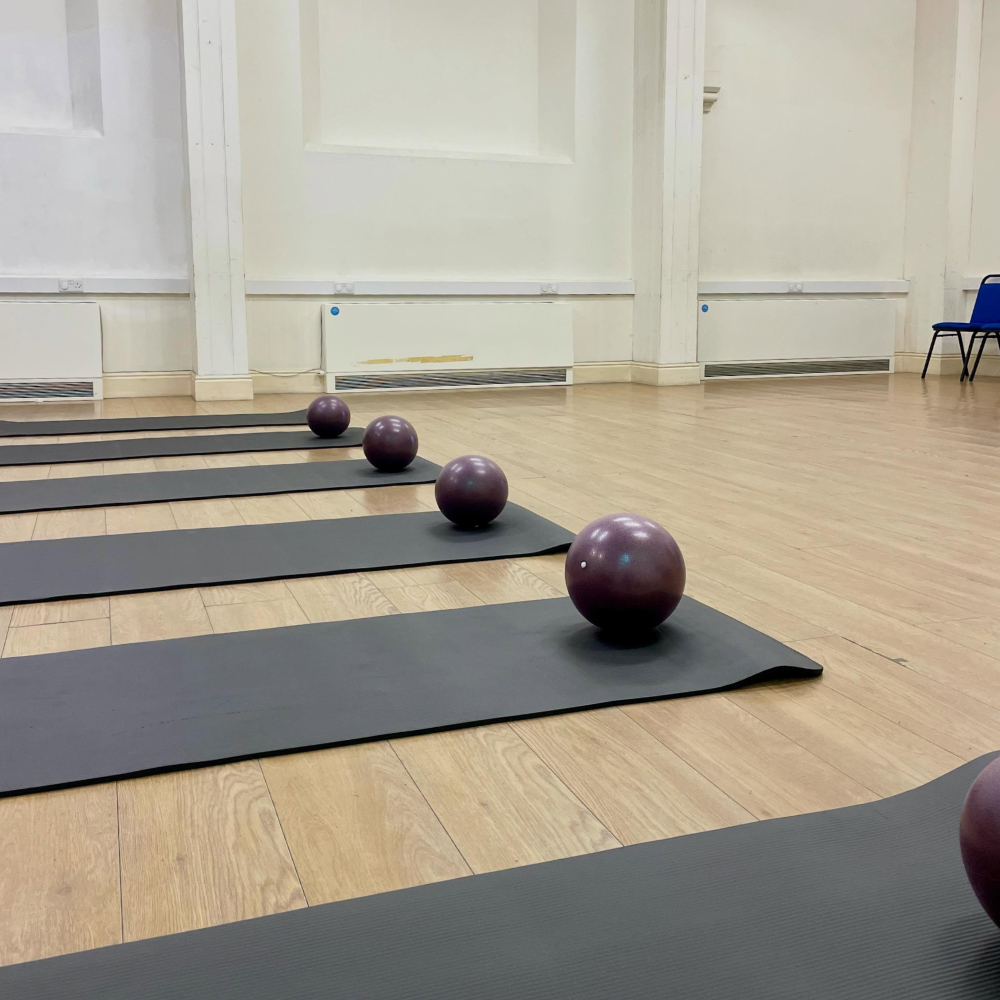 Mats and pilates balls set up in a studio.
