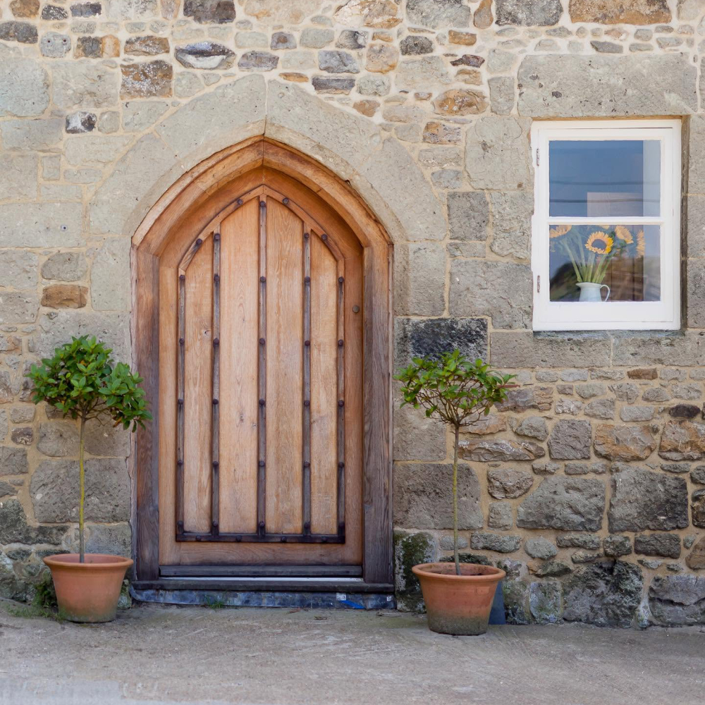 A wooden gothic door on a stone building.