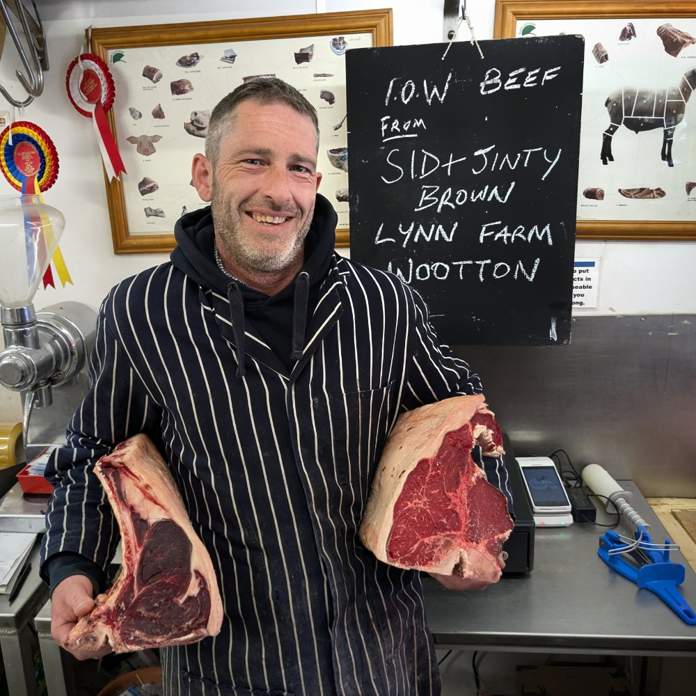 A butcher holding two joints of meat.