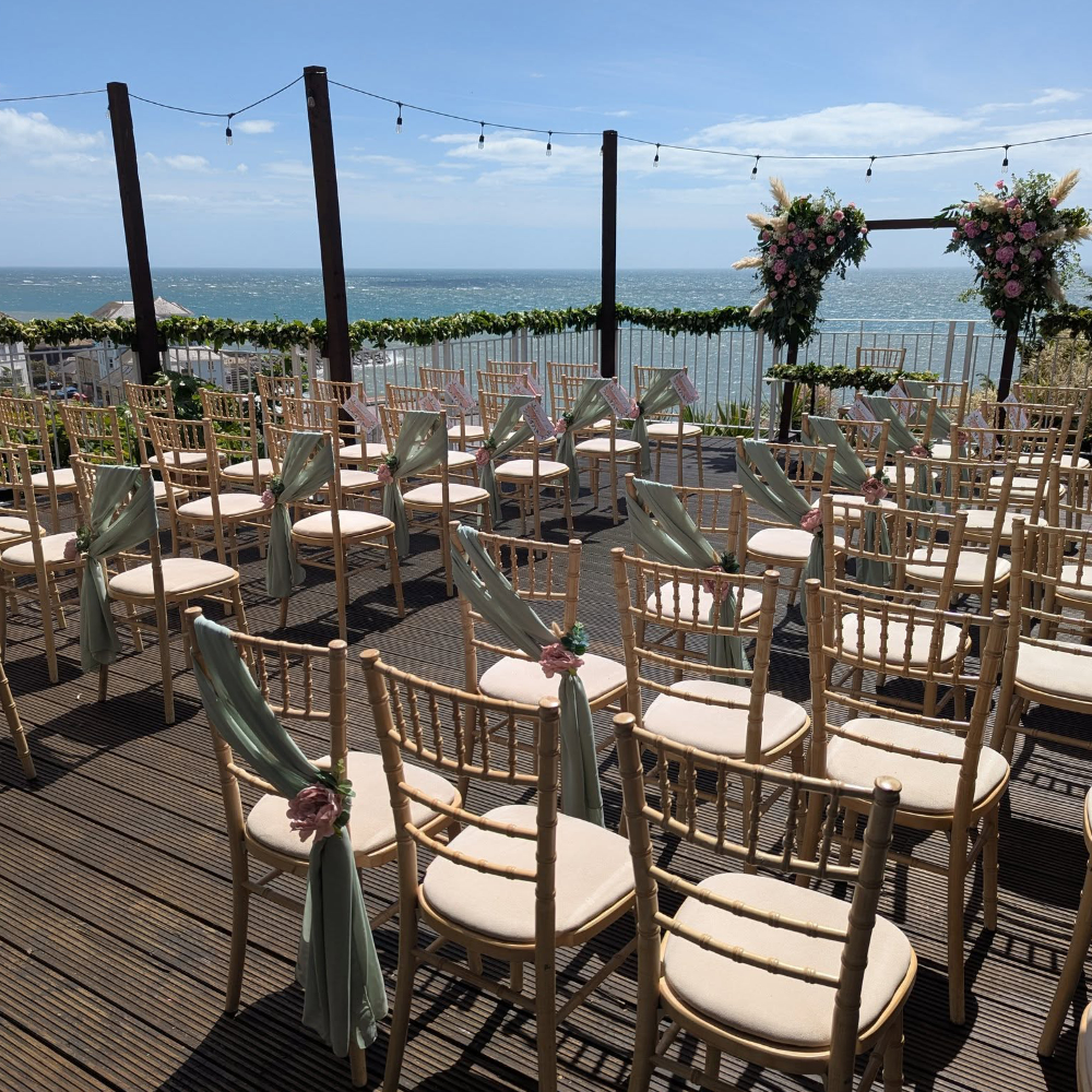 A deck facing the sea set up with seating for a wedding.