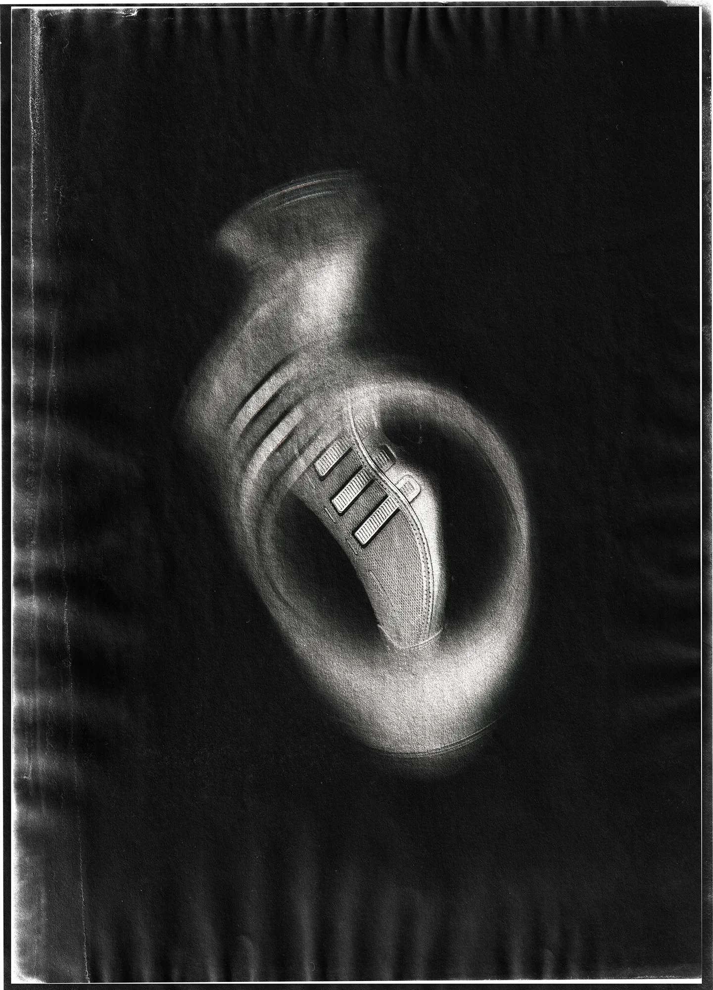 Black-and-white image of an Adidas sneaker floating against a dark background, surrounded by circular motion blur, with a textured, film-like border that emphasizes speed and energy.