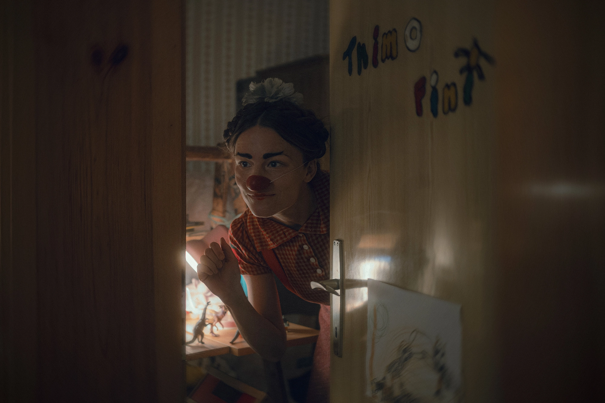 Nikolett Kustos photographed Film Still from movie Four Minus Three (Vier Minus Drei). A young woman(actress Valerie Pachner) dressed as a clown peeks.