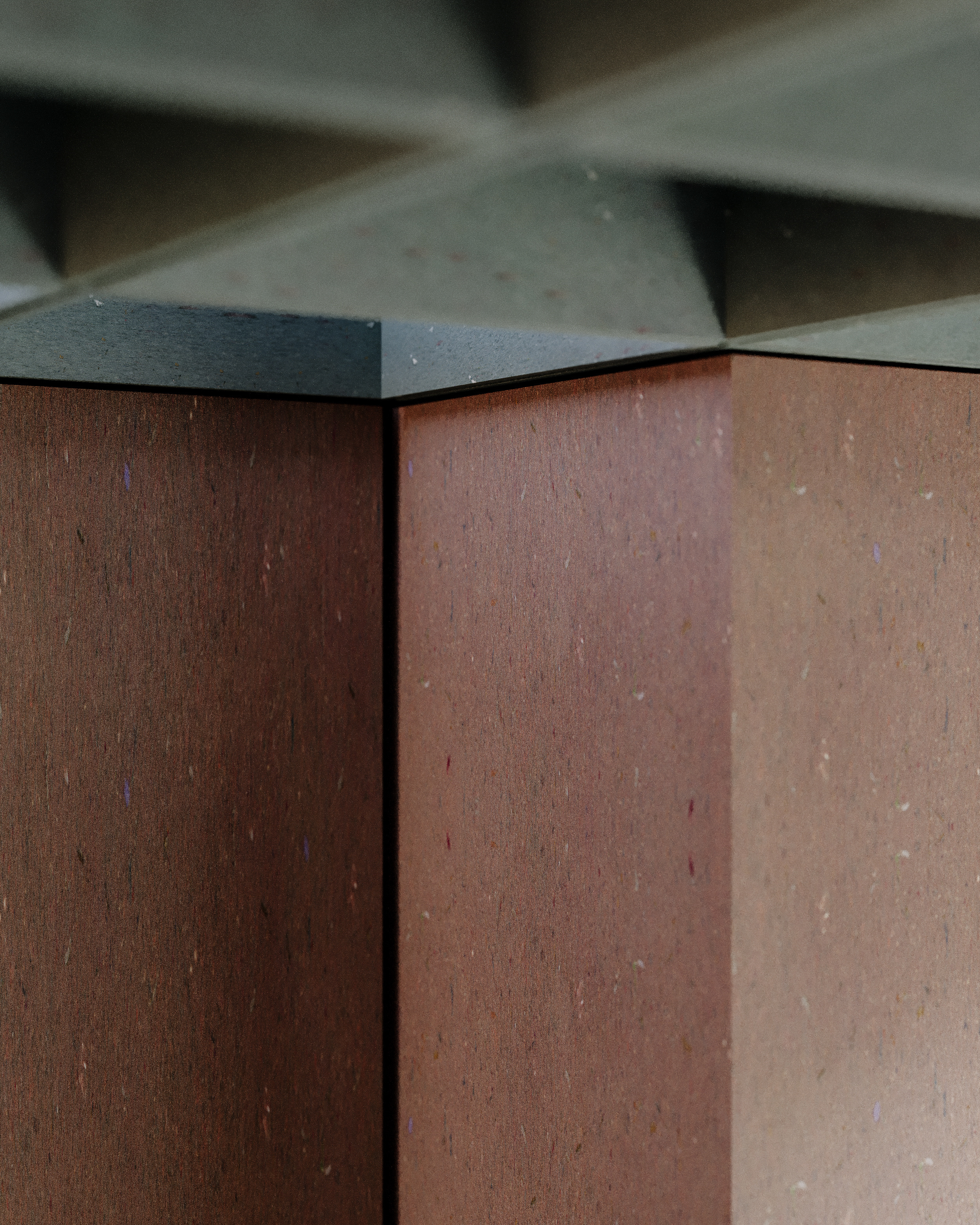 Close-up of a corner of a wooden table with a geometric, dark metal base.