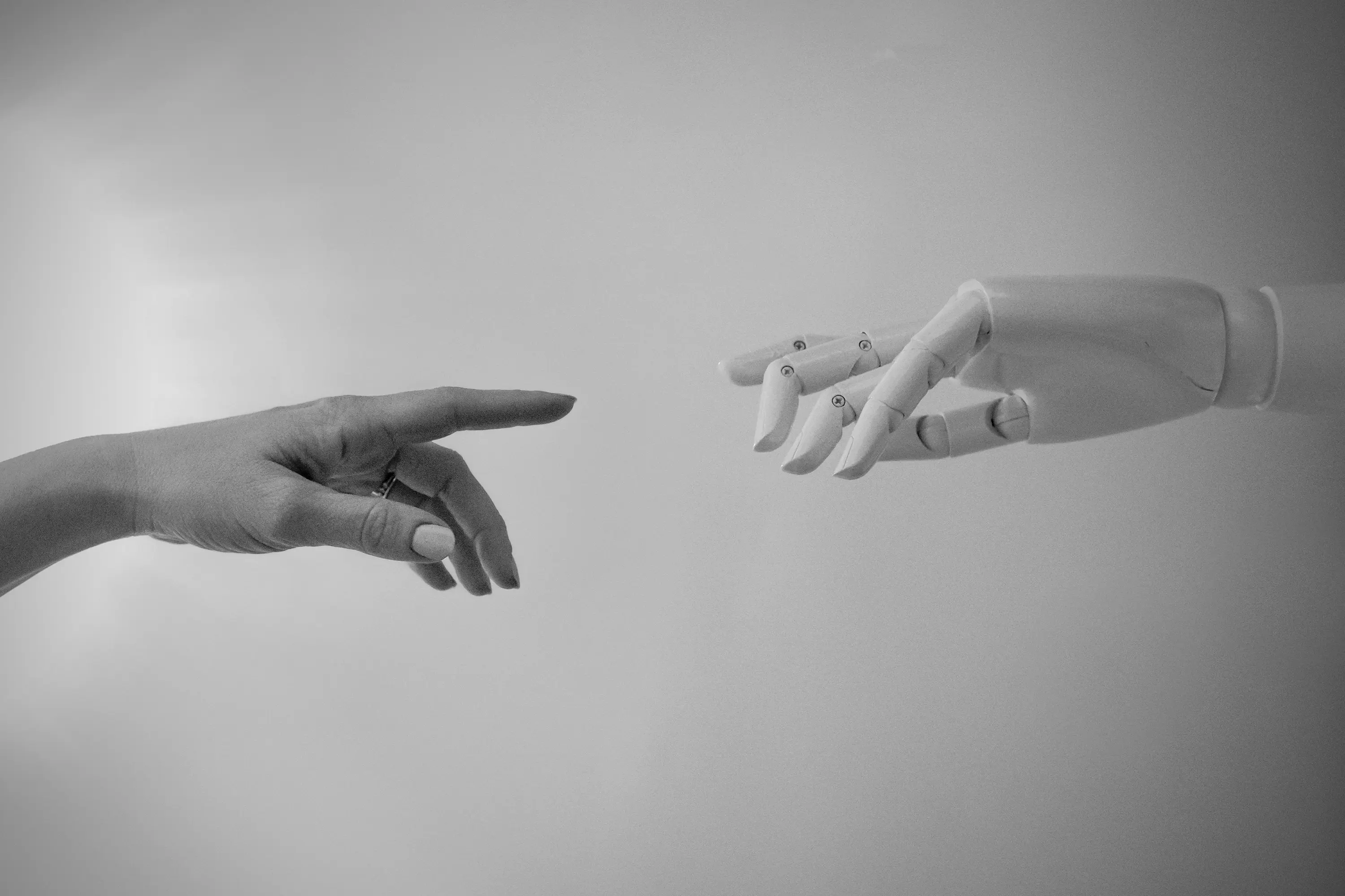 A human hand reaching toward a robotic hand, symbolizing human and AI collaboration