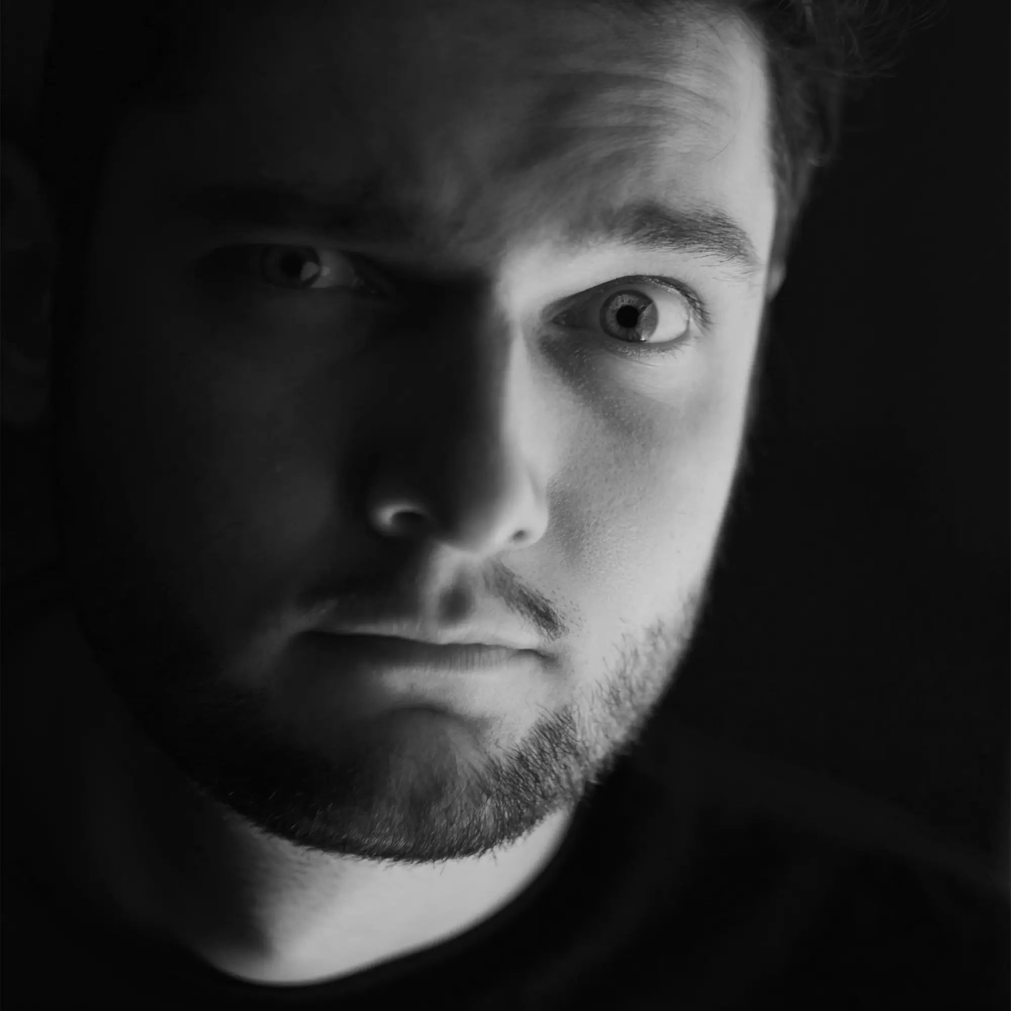 Close-up black-and-white portrait of a person with a surprised, questioning expression