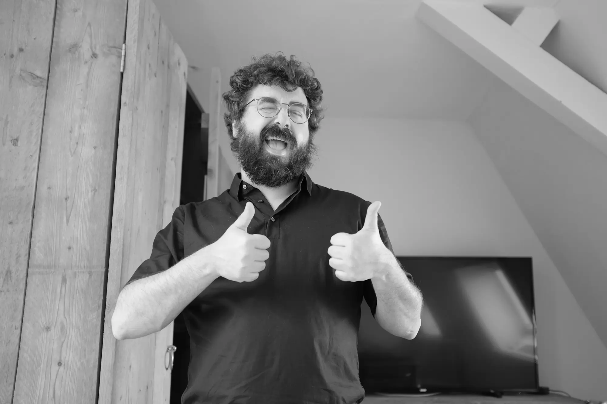 A smiling man giving two thumbs up, black and white