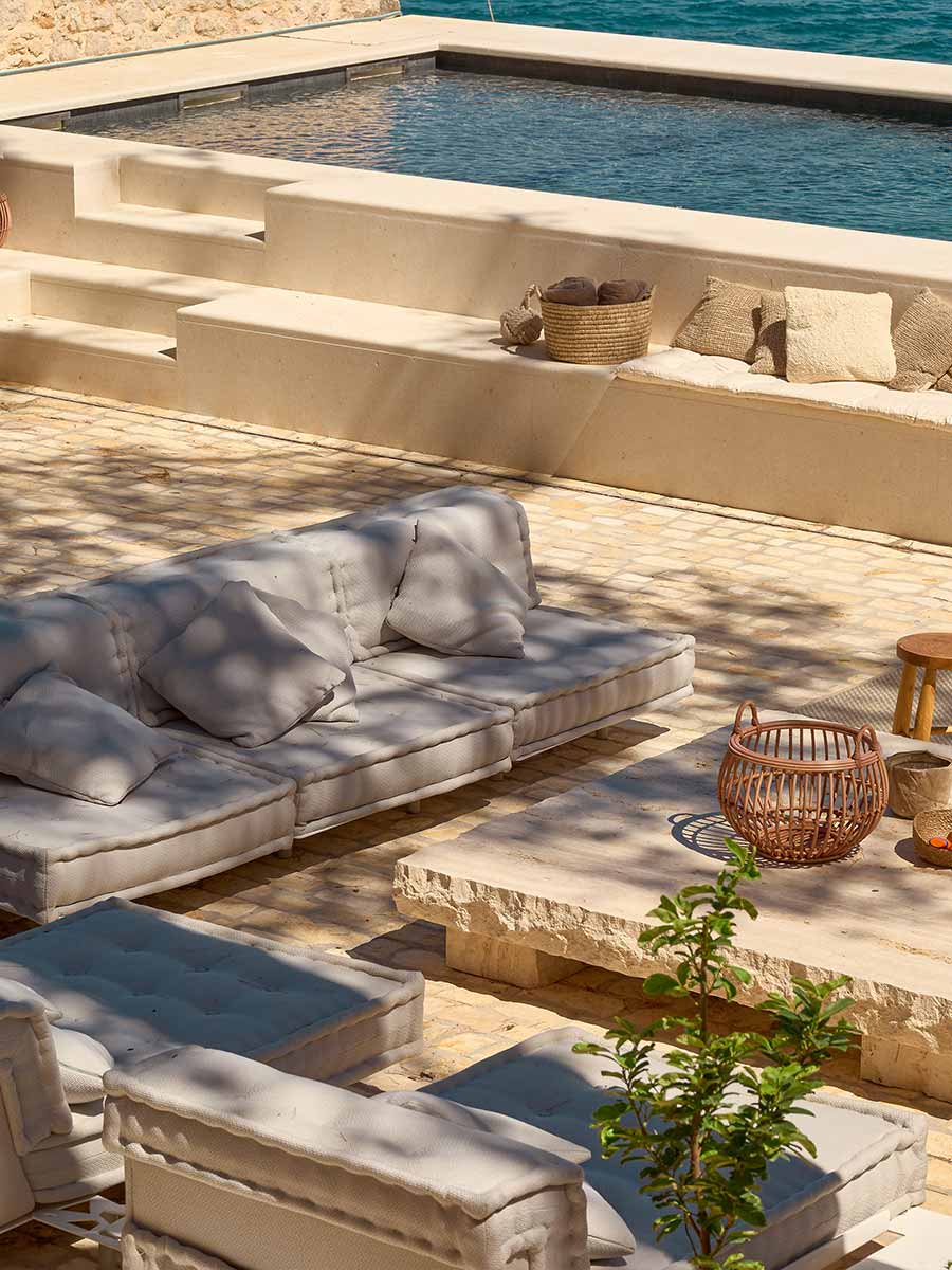 Outdoor lounge area with natural fiber seating and stone accents, creating a relaxed Mediterranean ambiance.