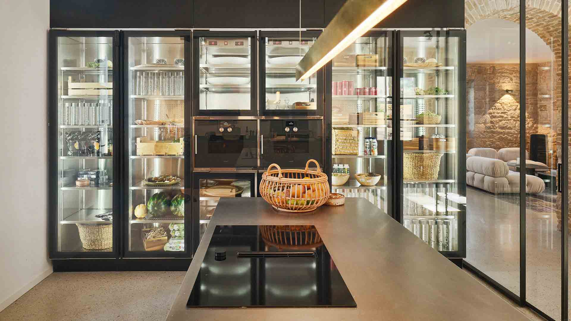 Spacious luxury kitchen with integrated appliances, abundant fresh produce, and a gold-toned statement pendant light.