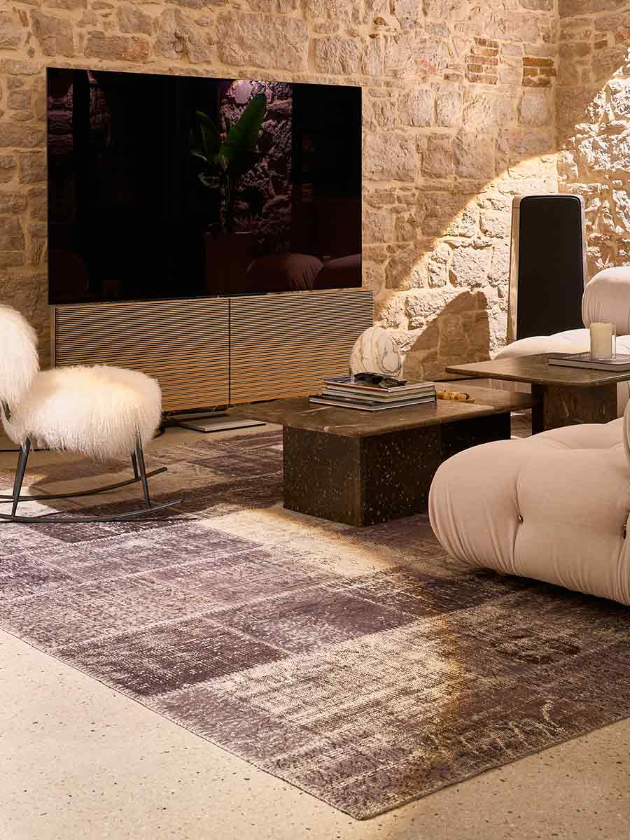 Contemporary living room featuring elegant furniture arrangements and a large integrated television in a warm, refined lighting scheme.