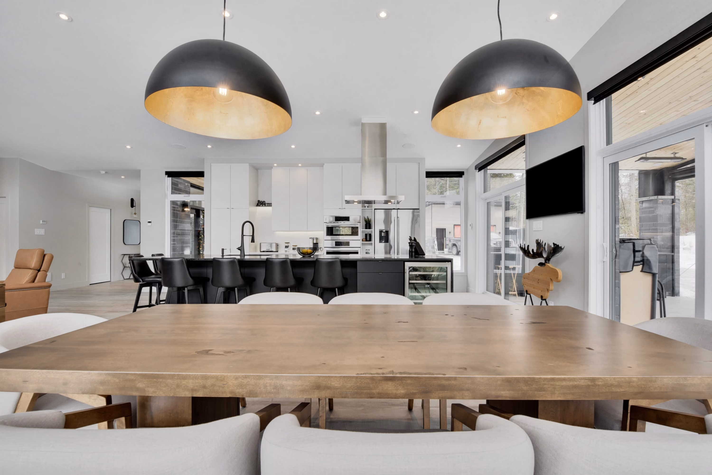 Intérieur de cuisine ouverte moderne avec îlot central et luminaires suspendus en forme de dôme, reflétant un design épuré et contemporain, une réalisation de Constromax.