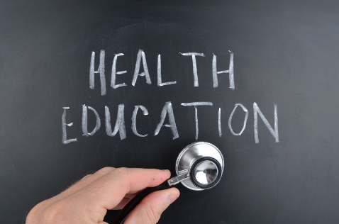 Text: Health Education written on chalkboard, hand with stethescope