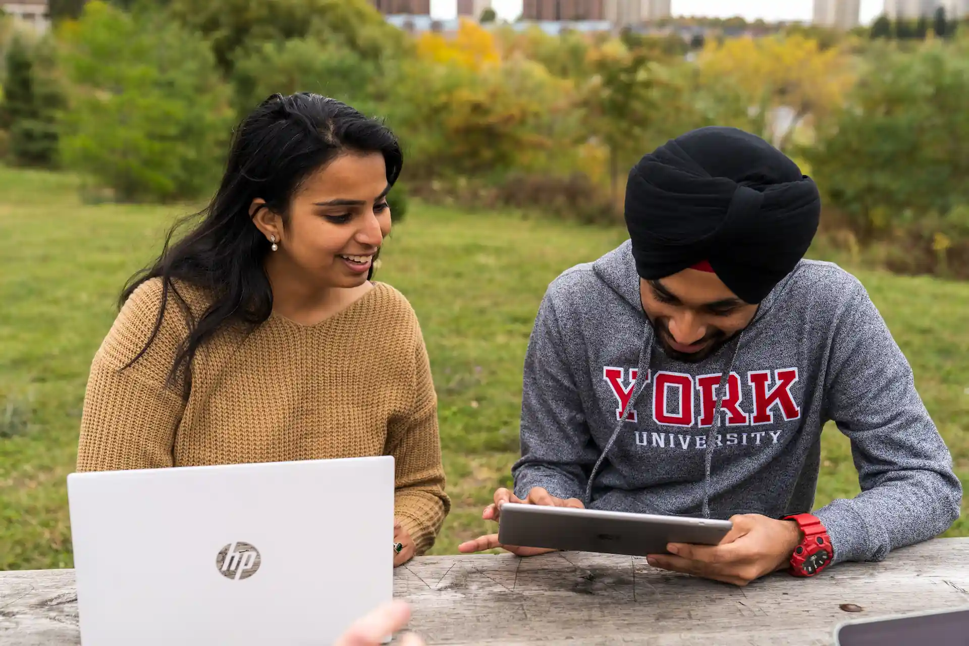 Two York University students using AppsAnywhere on a laptop and tablet outside.