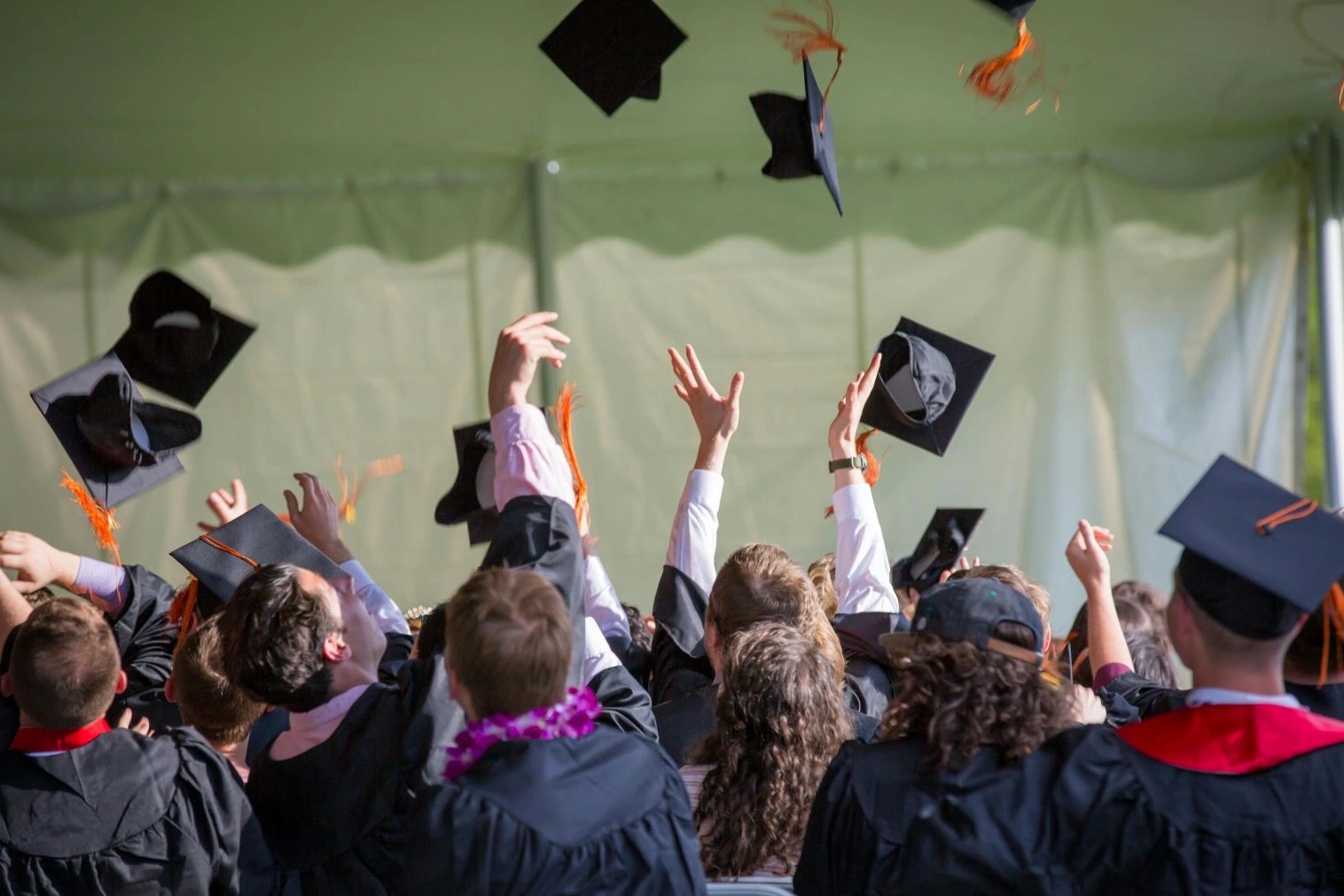 Students celebrating their graduation by throwing their mortarboards in the air