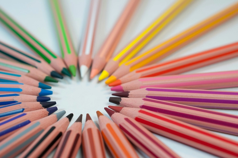 Colourful pencils lined up in a circle, forming a rainbow  coloured circle