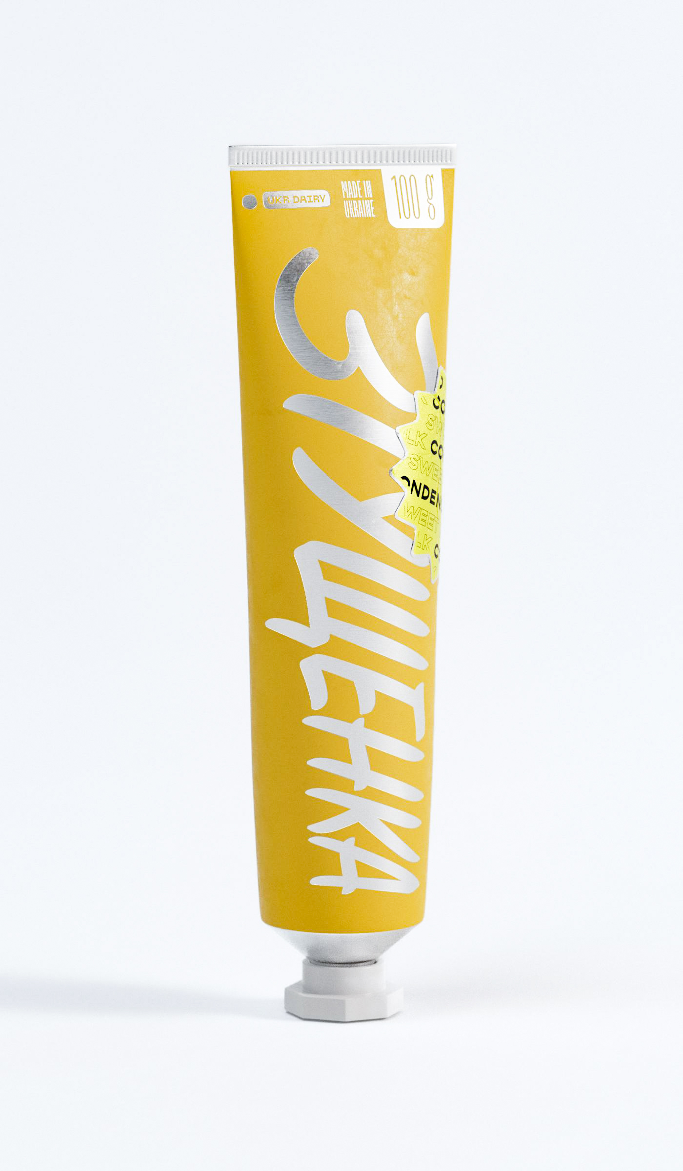 Complete brand narrative unfolds across this tubular packaging design, where script typography dances with geographic authenticity markers reading "MADE IN UKRAINE" and "100g" specifications. Design studio brilliance lies in orchestrating multiple typographic voices—from expressive brush lettering to utilitarian product details—into harmonious composition. Golden colorway suggests richness while maintaining approachability, exemplifying how packaging design transcends mere containment to become brand storytelling vehicle in competitive dairy marketplace.