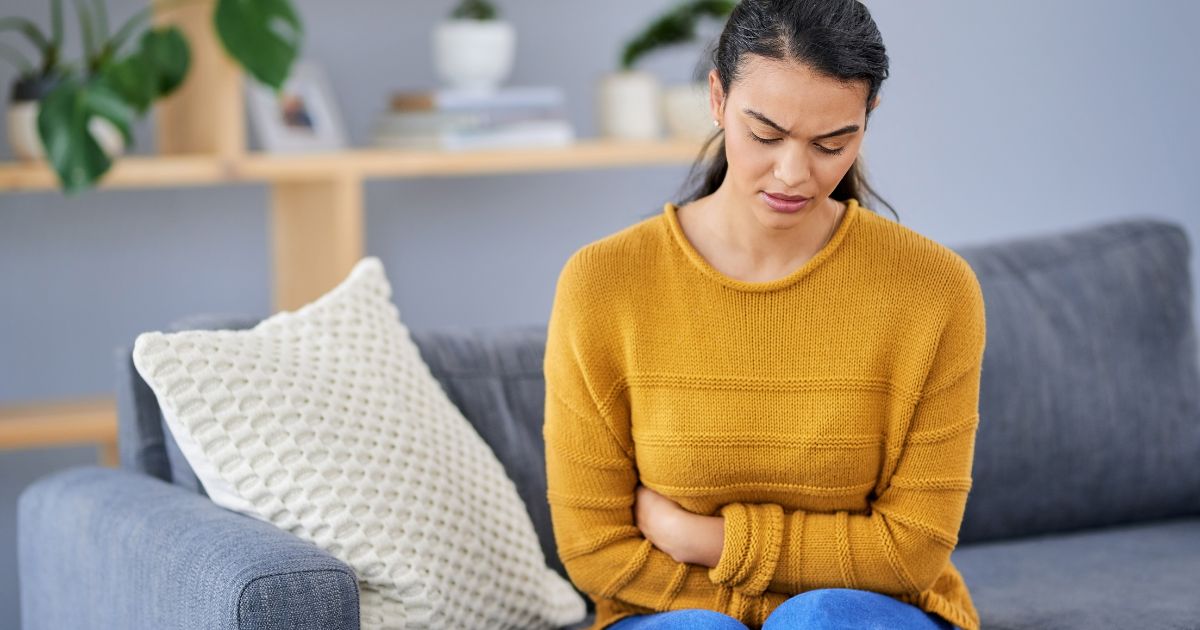 Woman holding bloated stomach experiencing digestive discomfort after eating