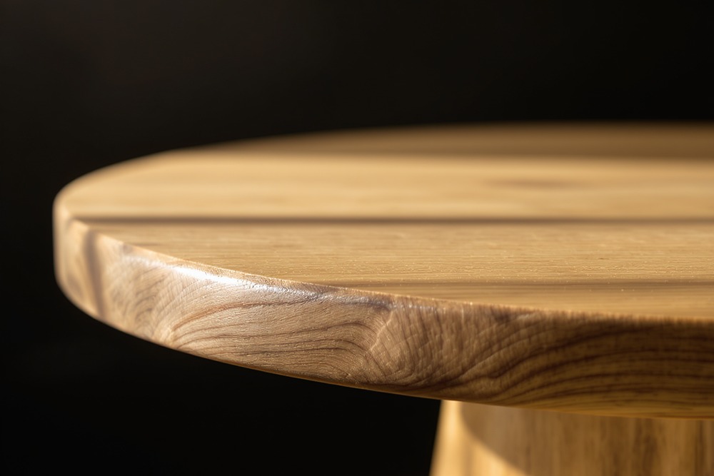 Close-up of a rounded wooden table edge in warm light - natural wood texture as a soft background