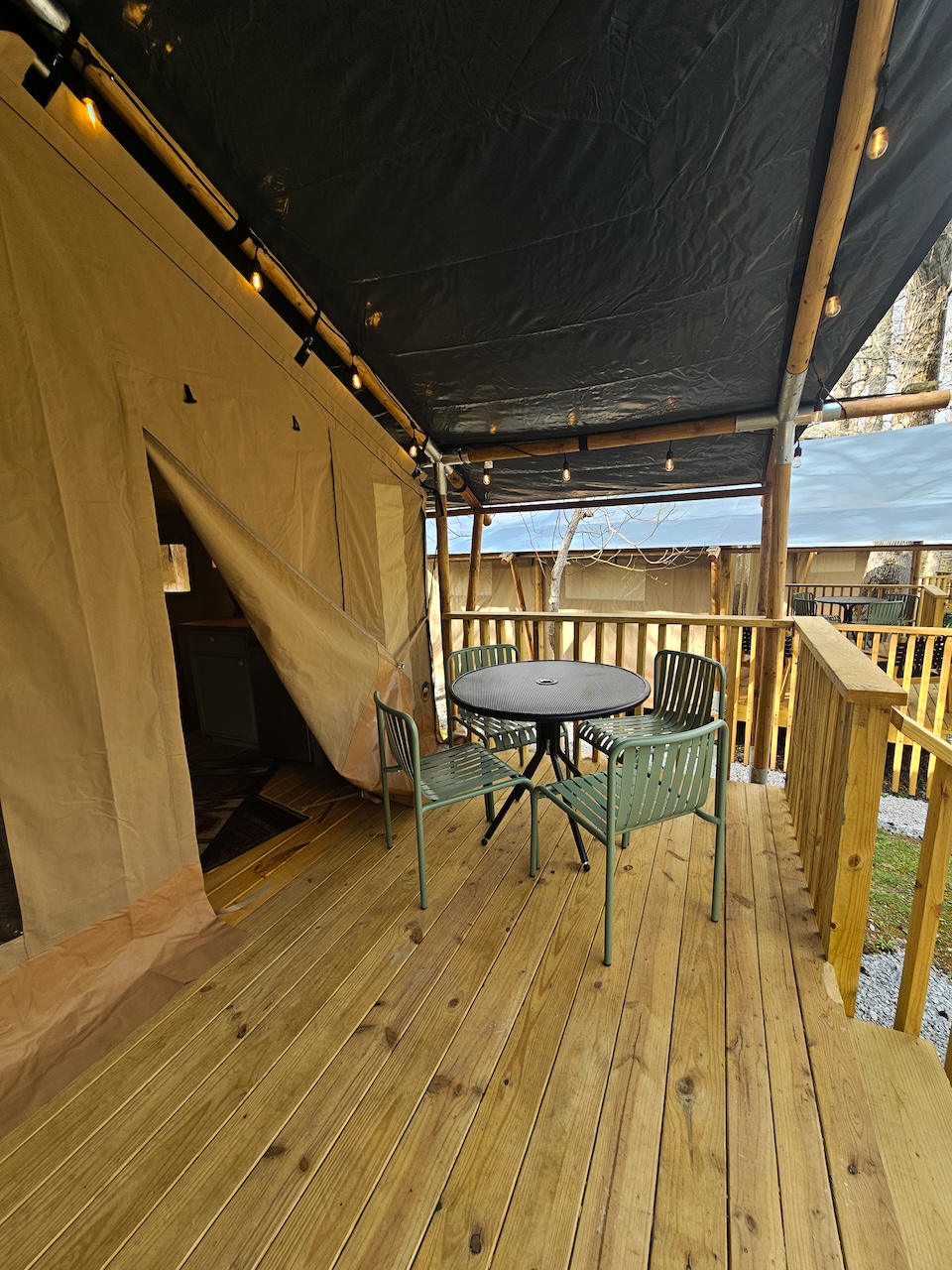 Exterior porch of a Safari Tent at Roamstead looking out toward the wooded campground.