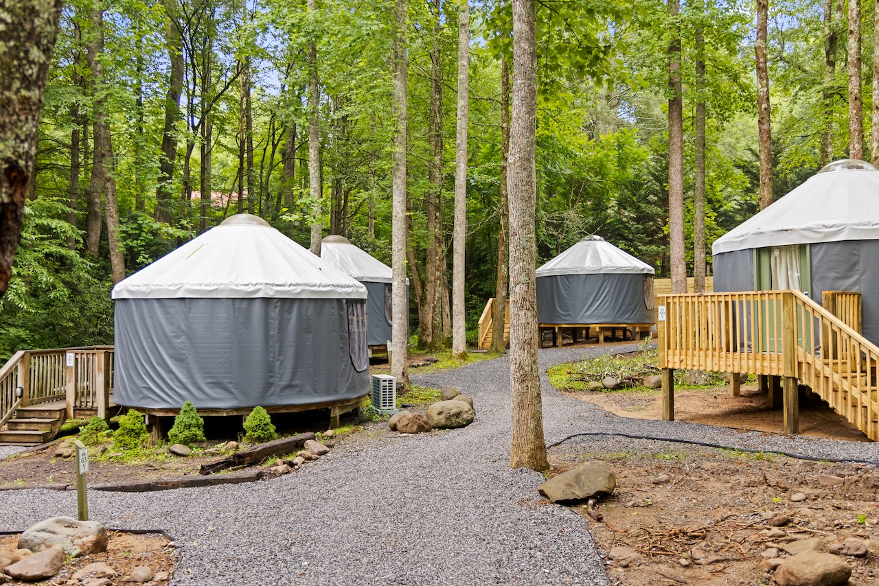 Exterior of silver modern yurts with wooden decks and gravel paths at Roamstead.