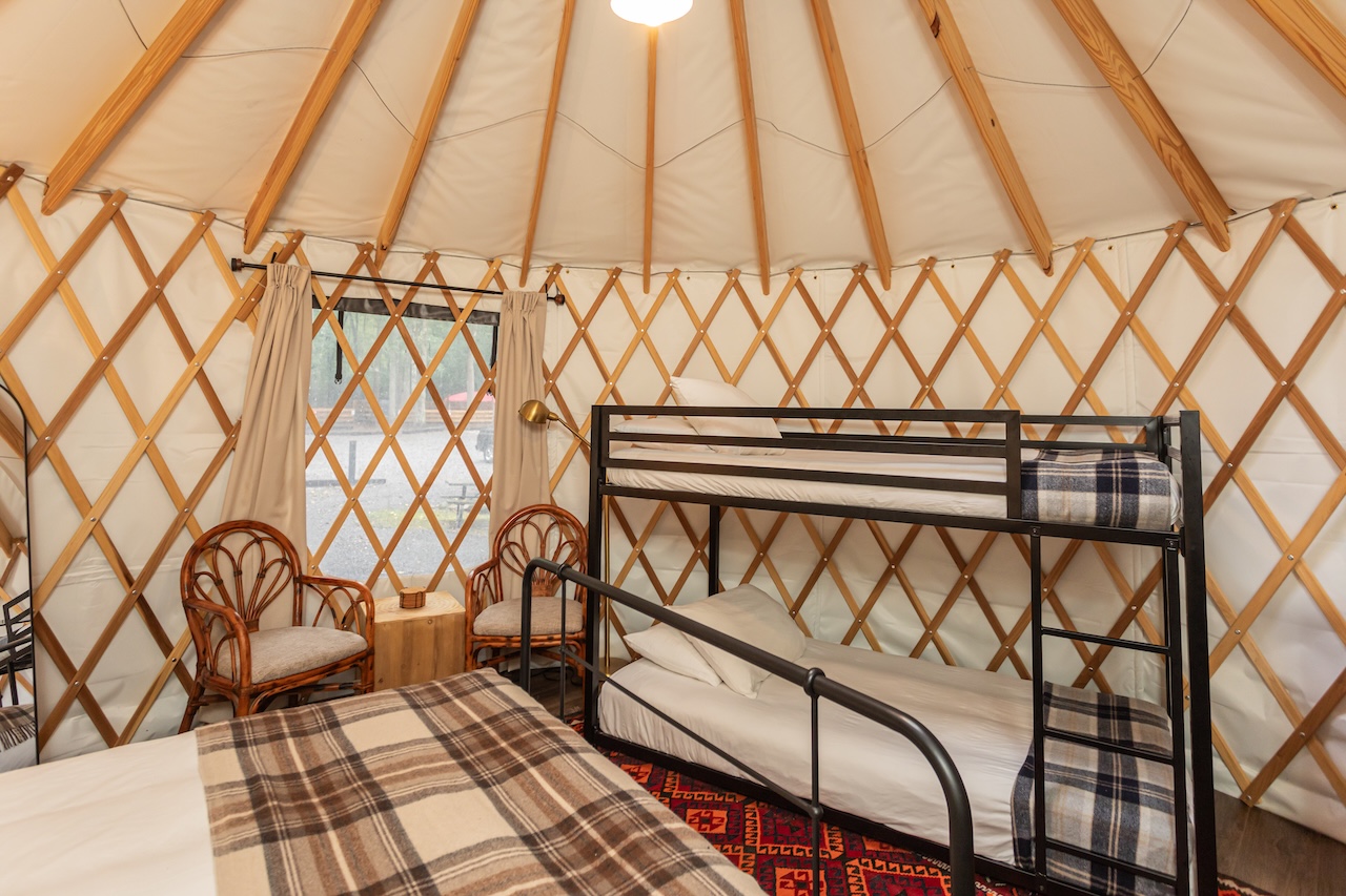 Interior of a Roamstead yurt featuring a wooden lattice frame and black metal bunk beds.