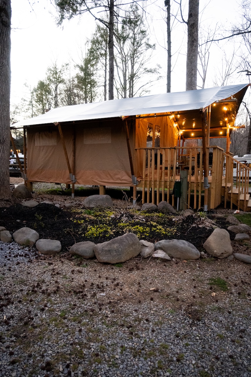 Luxury Safari Tent at Roamstead at dusk with warm interior lighting and stone landscaping.