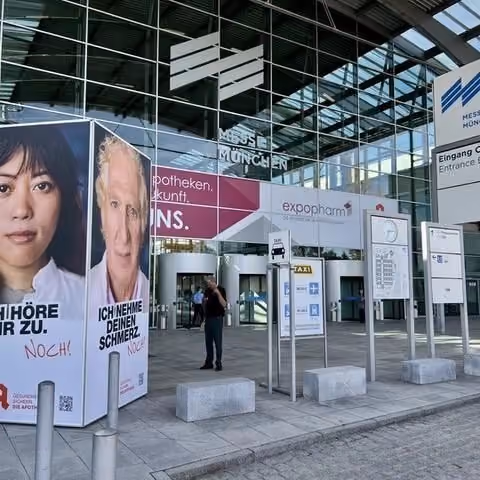 Entrance to Messe München with large posters and signs directing to expopharm event and taxi stand.