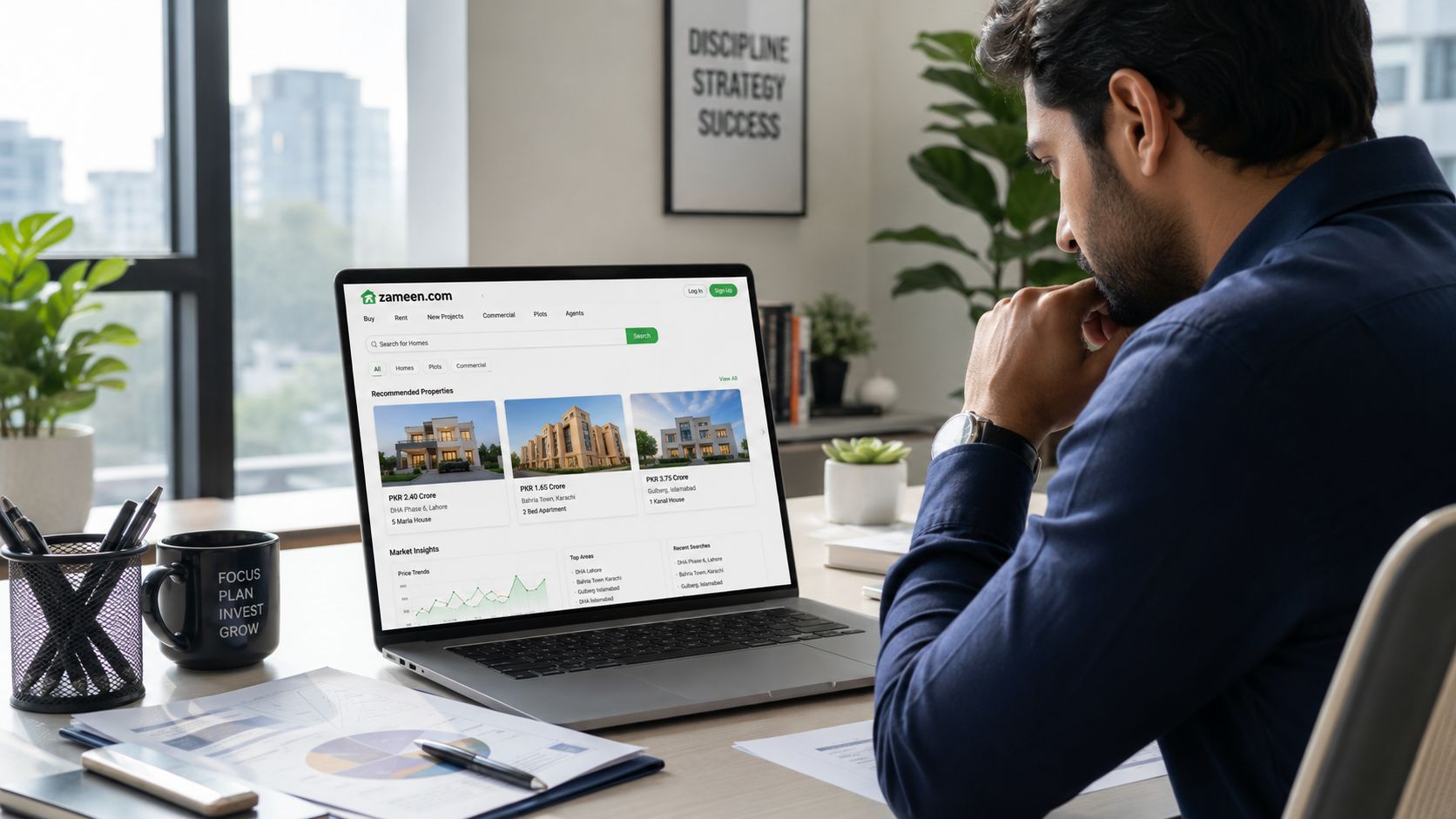 A professional man reviewing real estate listings on the Zameen.com website on his laptop at a desk.
