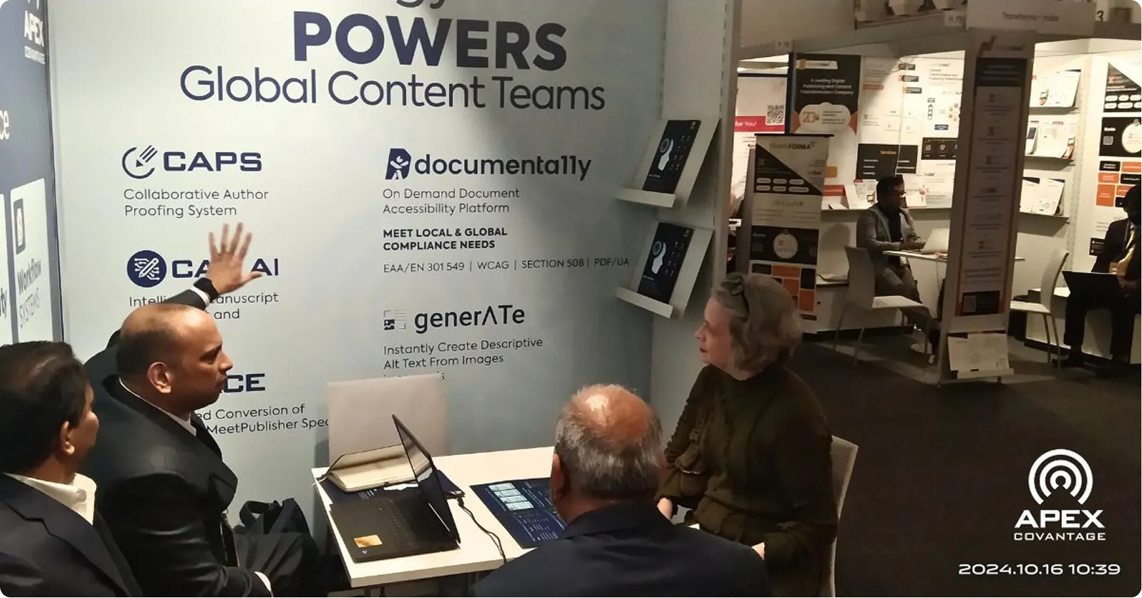 Four people sitting at a table in a booth with signage for powers global content teams and tech logos.