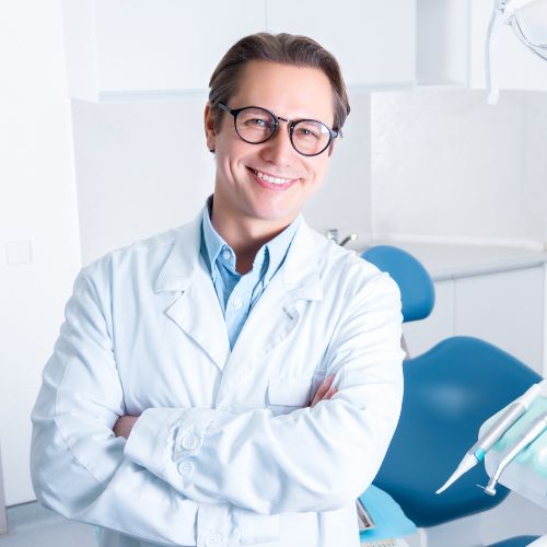 a smiling dentist standing in front of a dental chair