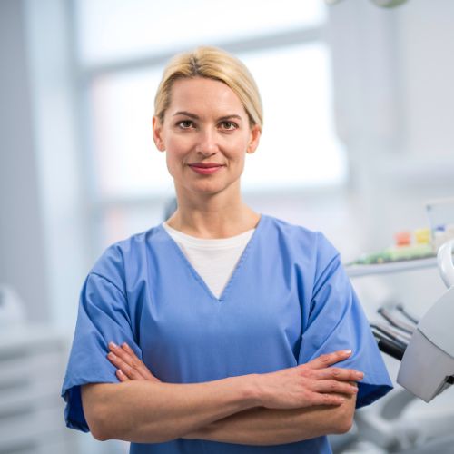a dentist in scrubs standing in a treatment room