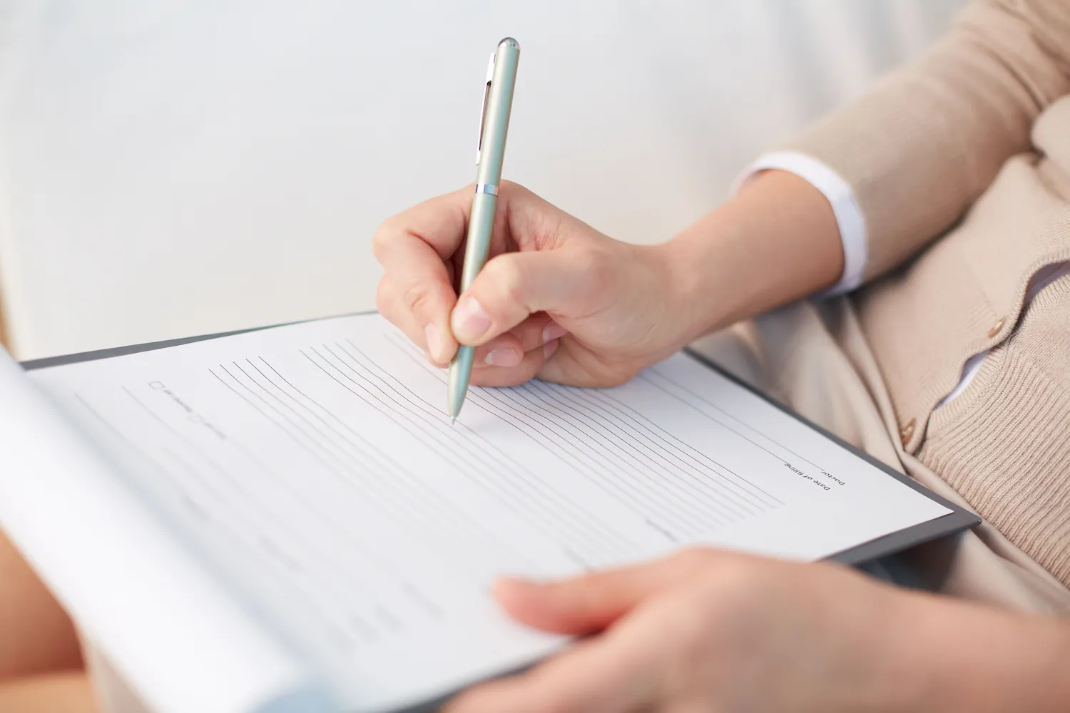 a person holding a pen and writing on a piece of paper