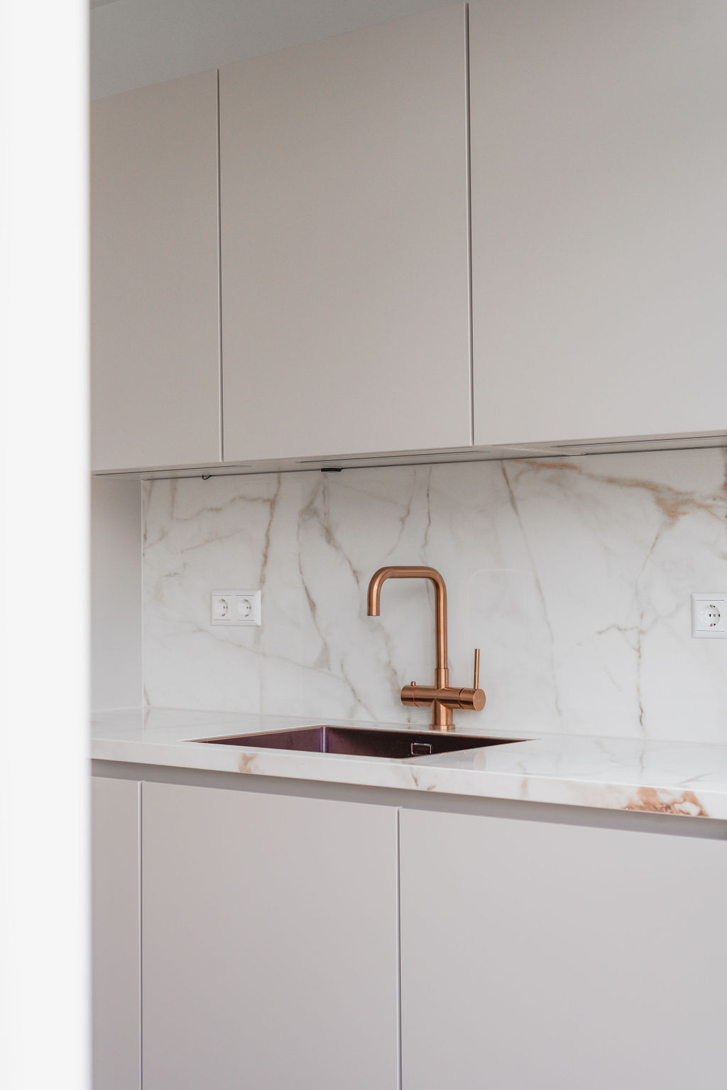 Moderne keuken met marmerlook eiland en koperen kraan
