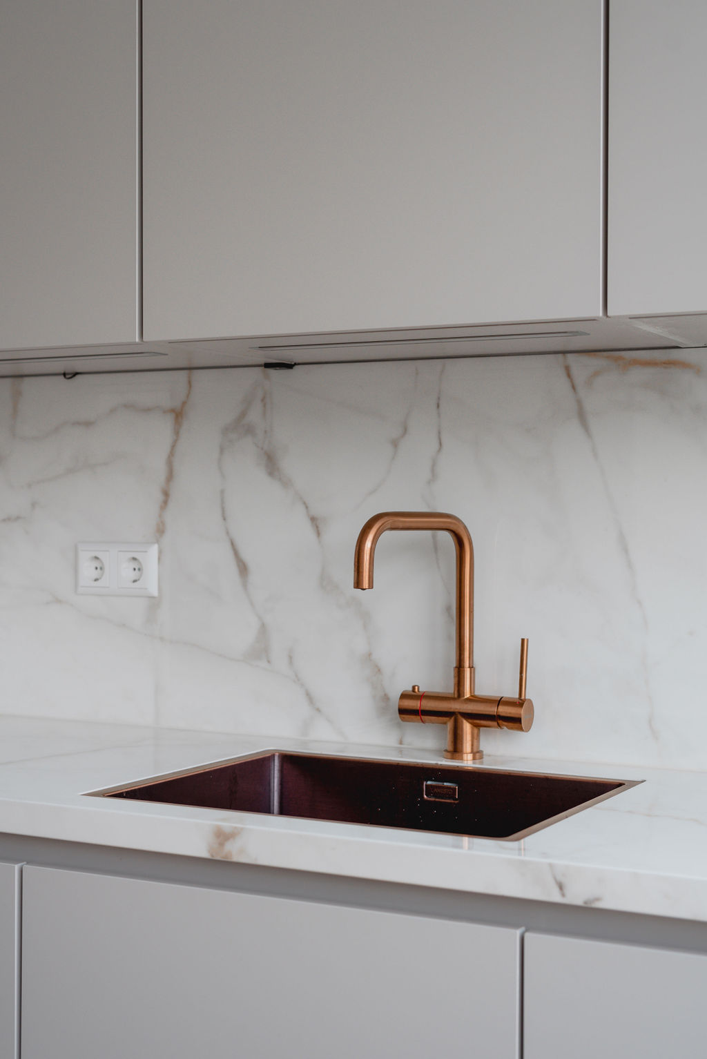 Moderne keuken met marmerlook eiland en koperen kraan