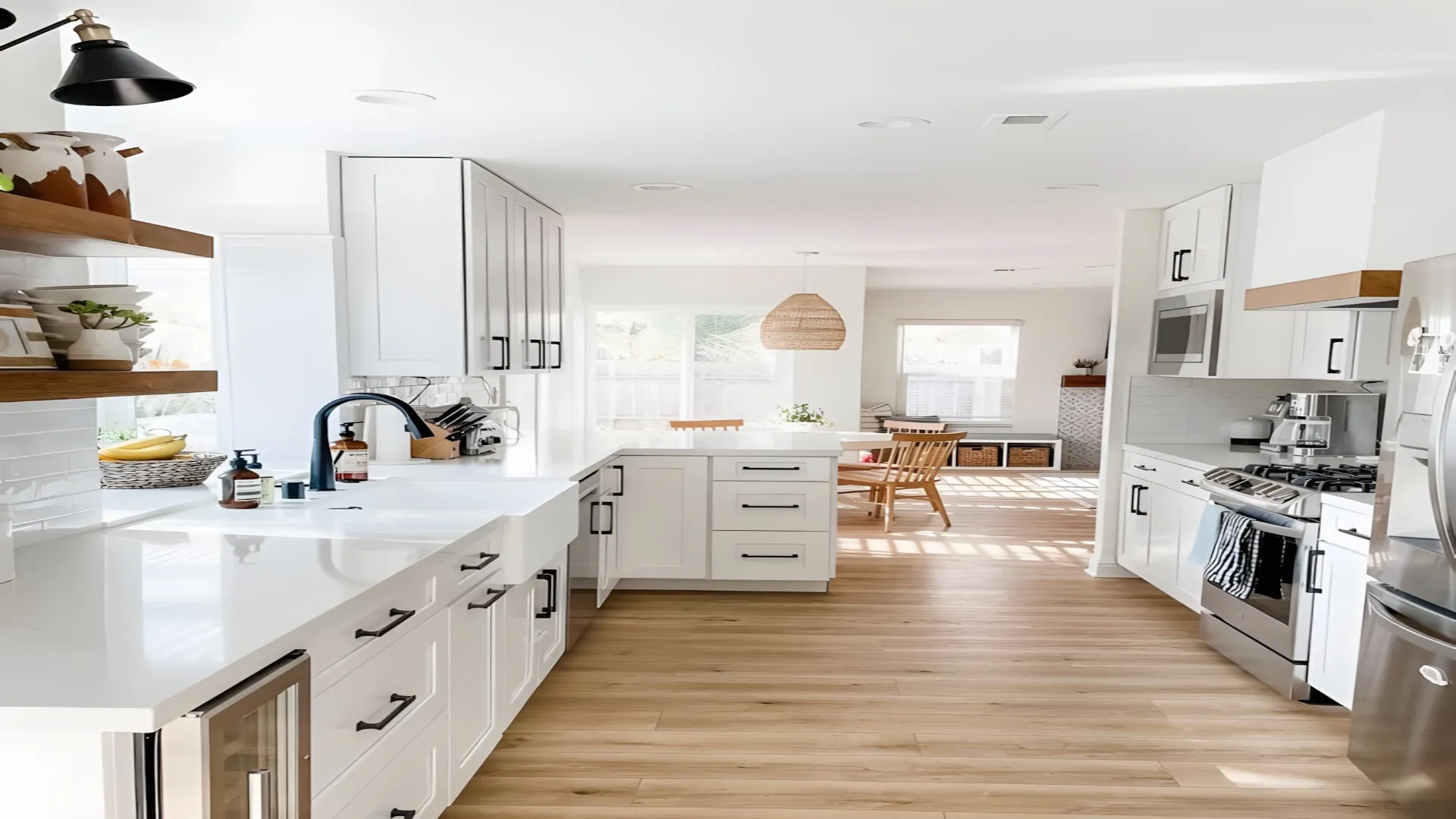White kitchen with open wood shelves, a black faucet and light wood floors
