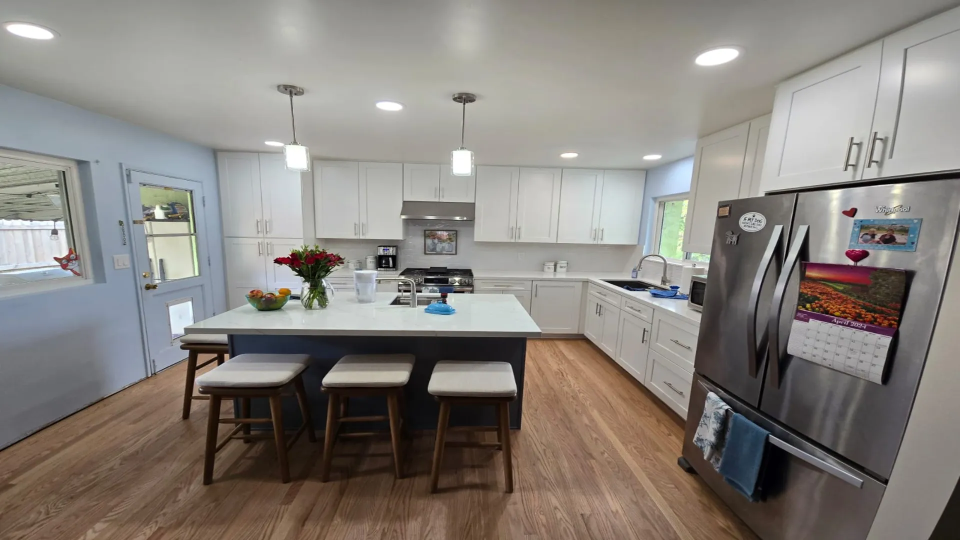 White kitchen with a navy island and pendant lights