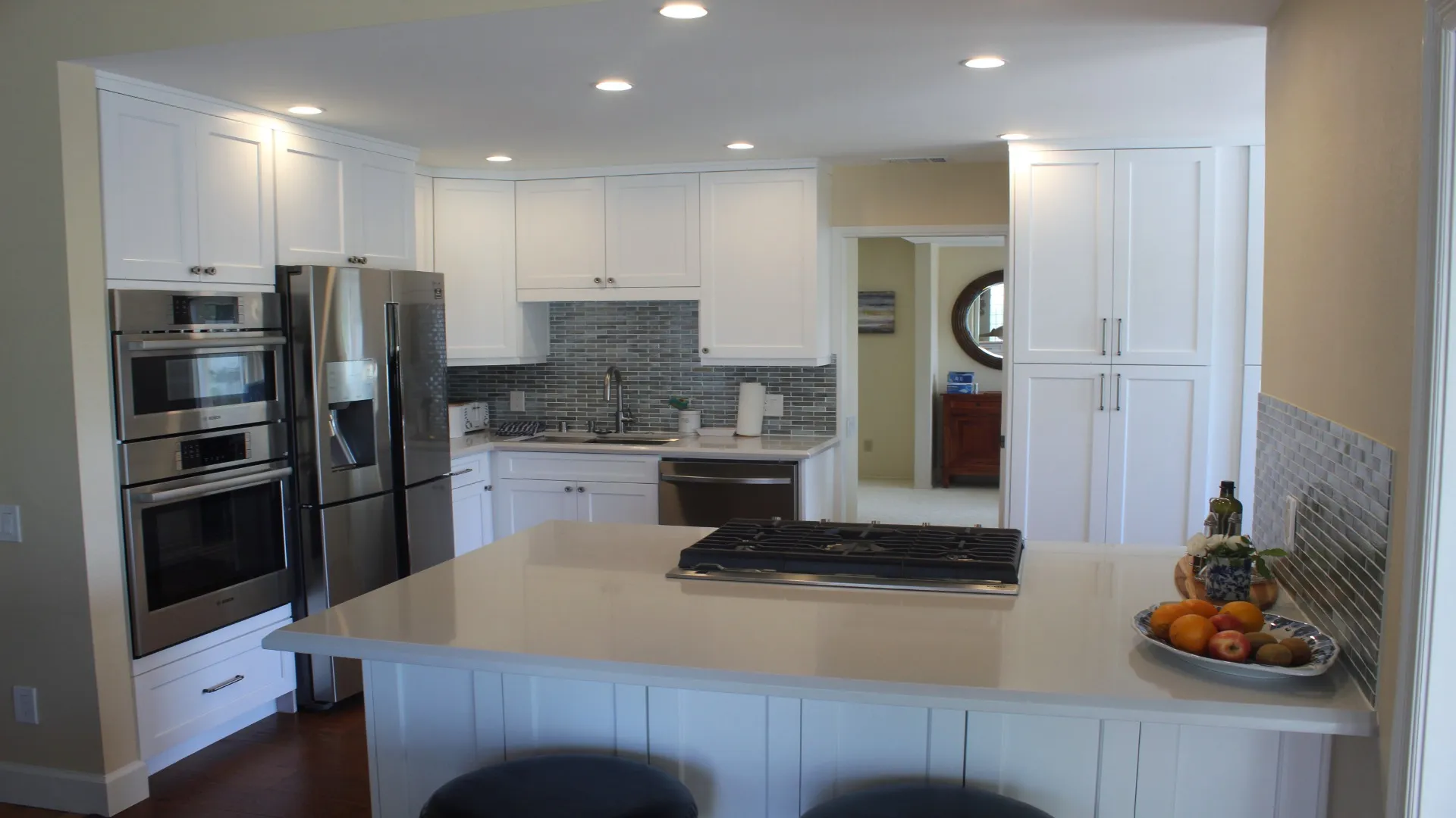 White kitchen with an island cooktop and double wall ovens