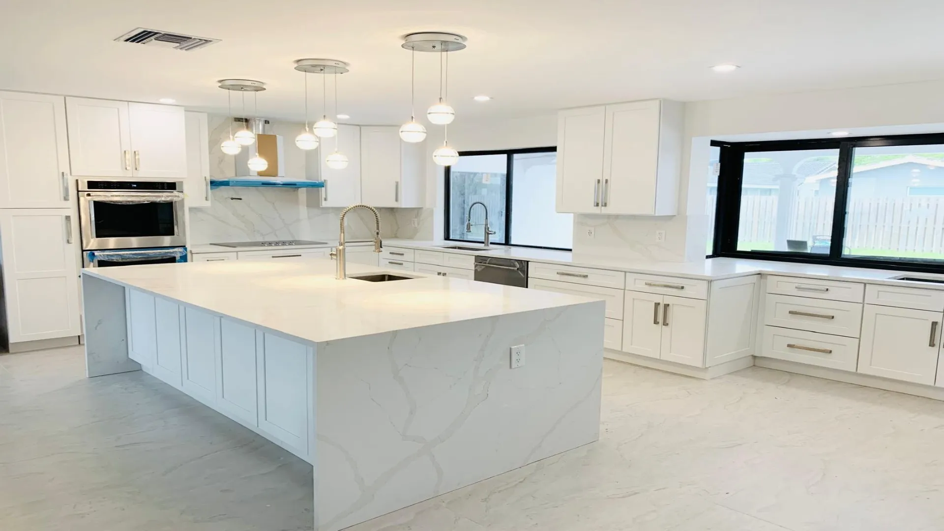 Open white kitchen with a waterfall island and modern pendants