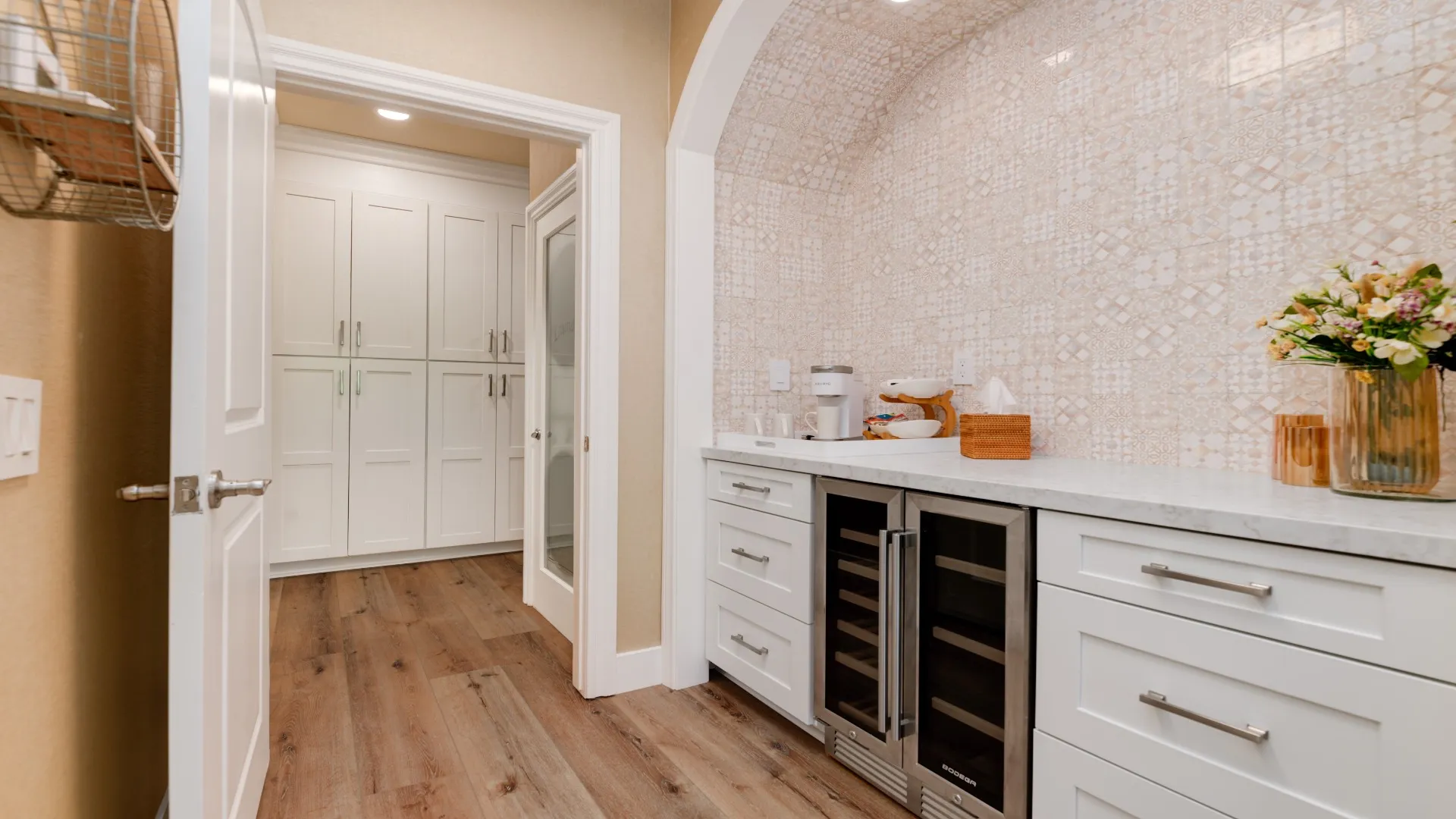 Butler’s pantry with a wine fridge and patterned tile under an arched ceiling