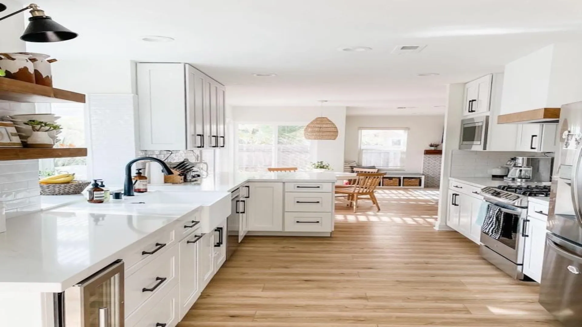 White kitchen with hardwood flooring, a peninsula, black faucet and floating wood shelves
