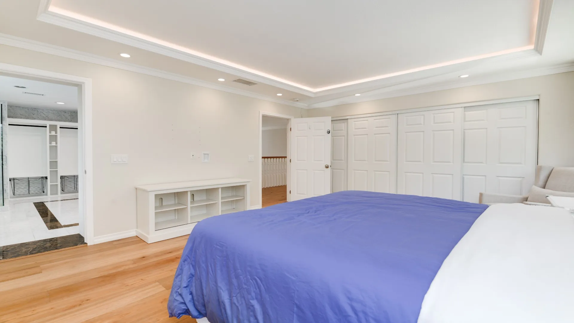 Bedroom with cove lighting, wood floors and paneled closet doors