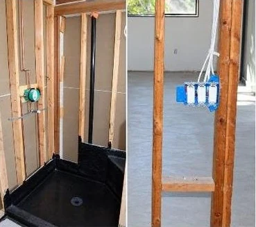 Shower pan and plumbing rough-in next to new electrical boxes in framed walls