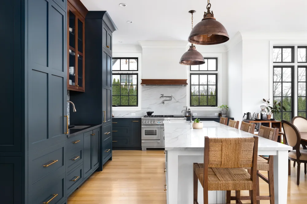 Navy kitchen cabinets with brass pulls and a marble island