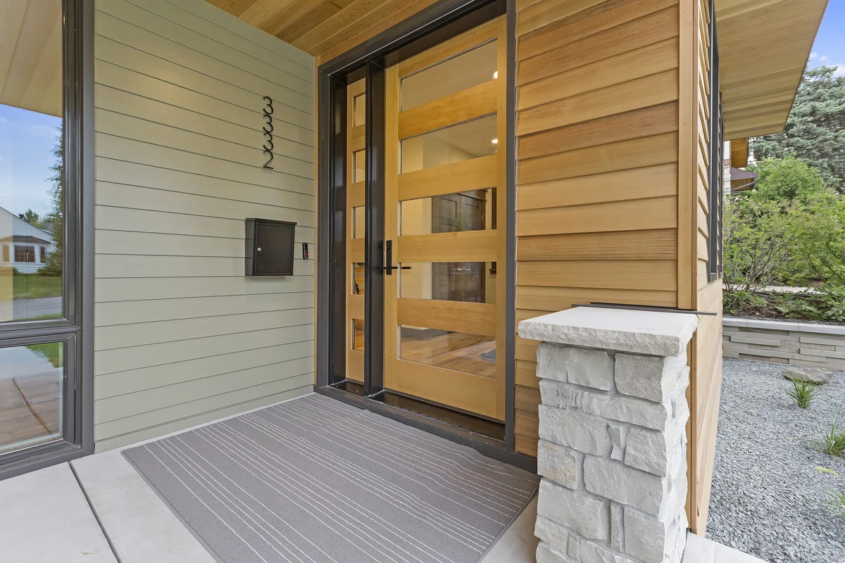 Modern front entry with wood siding and a glass-panel door