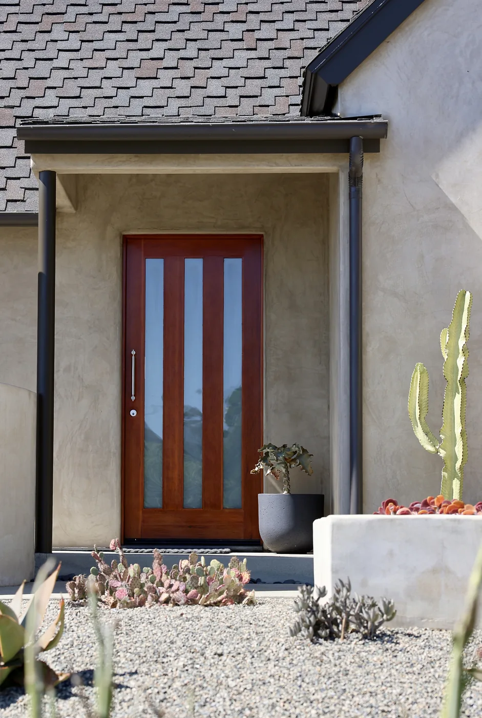 Stucco entry with a wood front door and desert plants