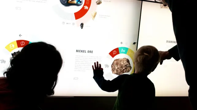 Visitors interacting with a multi-user touchscreen museum exhibit exploring minerals and everyday objects