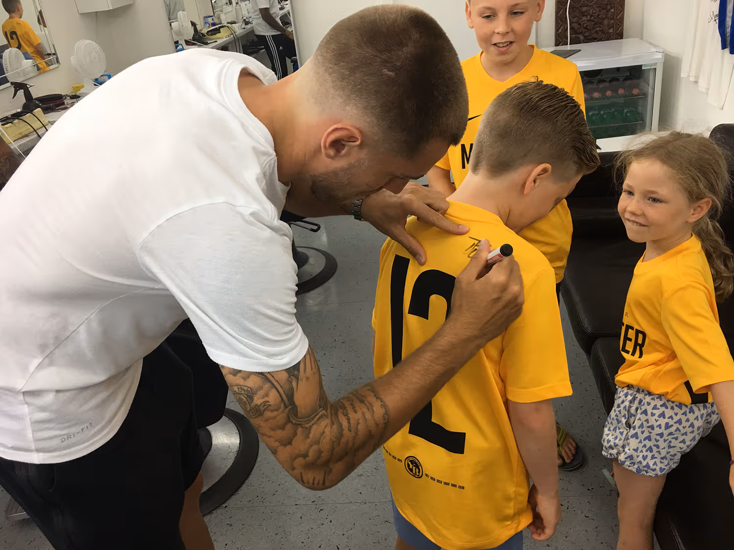 Former Young Boys player signing a fan's shirt at Fineboy Barbershop